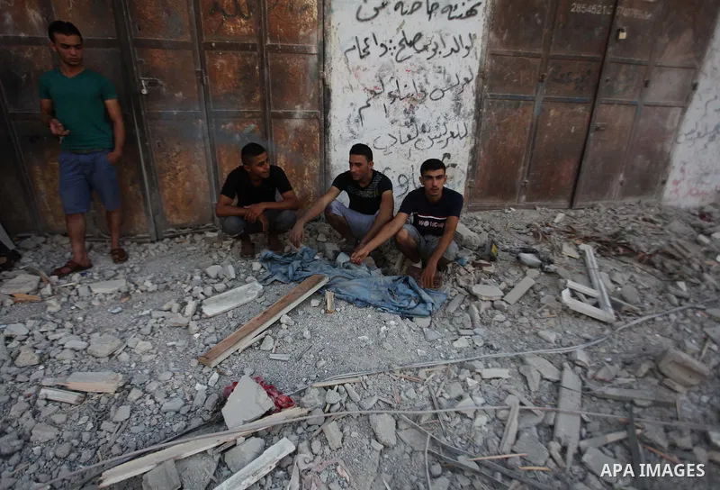 Palestinians sit on the remains of a house, which witnesses said was hit by an Israeli air strike, in Gaza City August 24, 2014. Israel launched more air strikes on Gaza on Sunday after taking its military campaign to a...