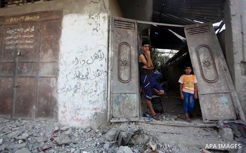 Palestinians stand on the remains of a house, which witnesses said was hit by an Israeli air strike, in Gaza City August 24, 2014. Israel launched more air strikes on Gaza on Sunday after taking its military campaign to...