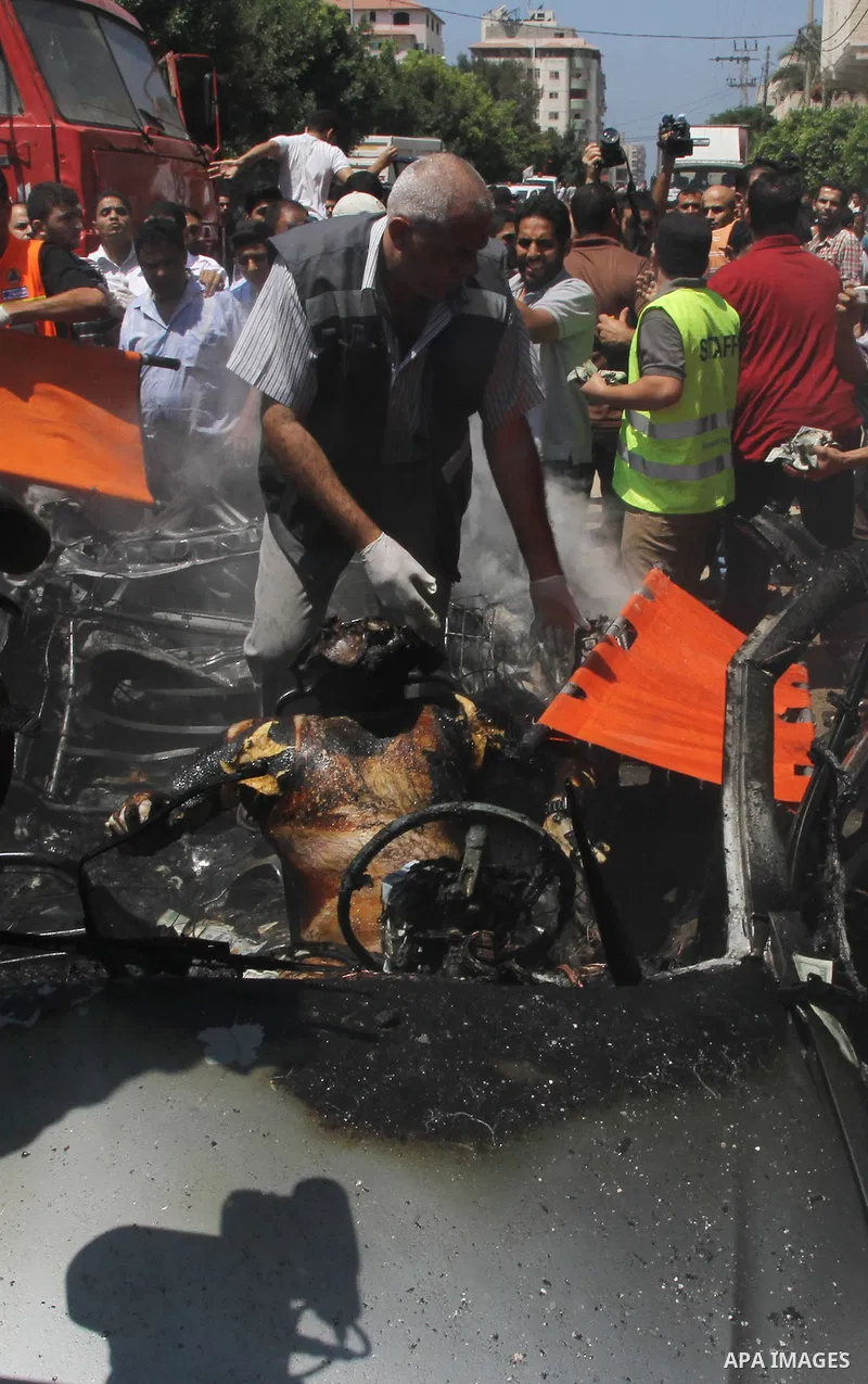 Palestinians gather around the remains of a car, which witnesses said was hit by an Israeli air strike, in Gaza City August 24, 2014. Israel launched more air strikes on Gaza on Sunday after taking its military campaign...