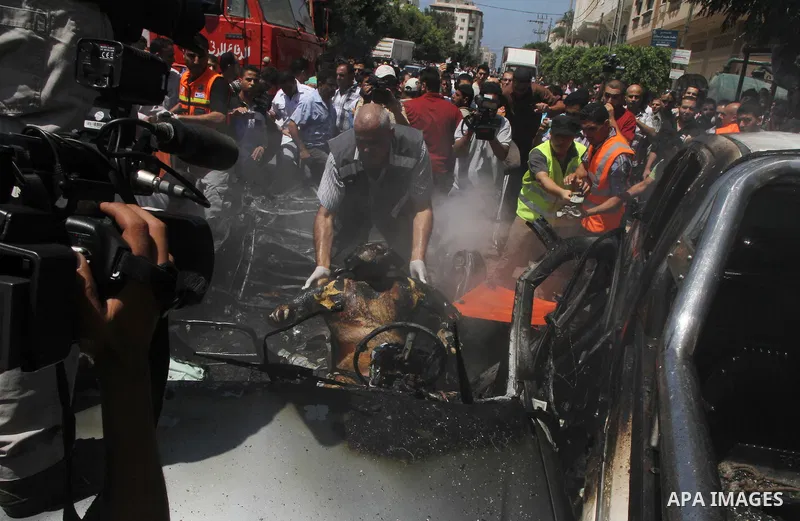 Palestinians gather around the remains of a car, which witnesses said was hit by an Israeli air strike, in Gaza City August 24, 2014. Israel launched more air strikes on Gaza on Sunday after taking its military campaign...