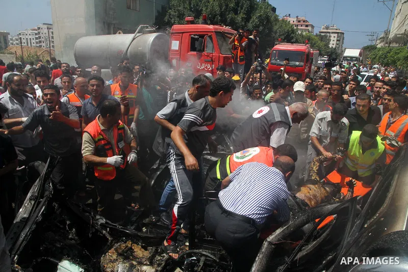 Palestinians gather around the remains of a car, which witnesses said was hit by an Israeli air strike, in Gaza City August 24, 2014. Israel launched more air strikes on Gaza on Sunday after taking its military campaign...