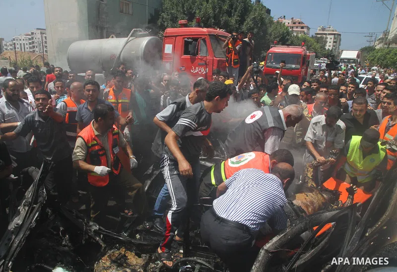 Palestinians gather around the remains of a car, which witnesses said was hit by an Israeli air strike, in Gaza City August 24, 2014. Israel launched more air strikes on Gaza on Sunday after taking its military campaign...