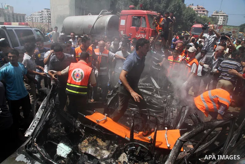 Palestinians gather around the remains of a car, which witnesses said was hit by an Israeli air strike, in Gaza City August 24, 2014. Israel launched more air strikes on Gaza on Sunday after taking its military campaign...