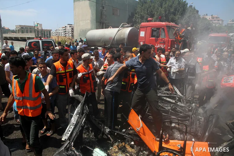 Palestinians gather around the remains of a car, which witnesses said was hit by an Israeli air strike, in Gaza City August 24, 2014. Israel launched more air strikes on Gaza on Sunday after taking its military campaign...