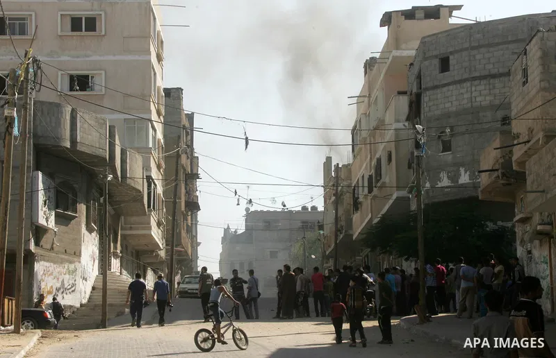 Palestinians run to take cover after an Israeli strike hits a building belonging to the Abu Marouf family in Khan Younis in the southern Gaza Strip, Sunday, Aug. 24, 2014. Photo by Abed Rahim Khatib