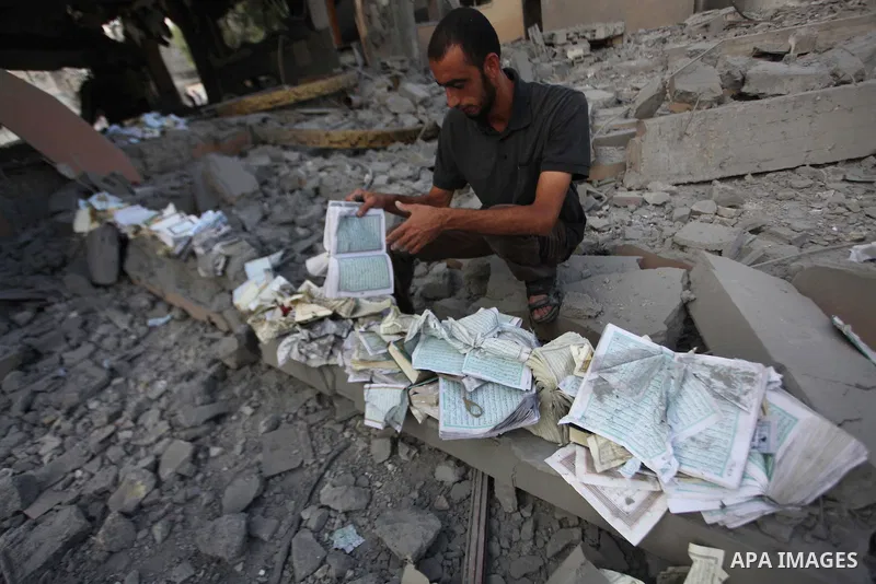 A Palestinian man collects pages of the Koran from the remains of a mosque, which witnesses said was hit by an Israeli air strike, in Beit Hanoun in the northern Gaza Strip August 25, 2014. Israel's Prime Minister Benjam...