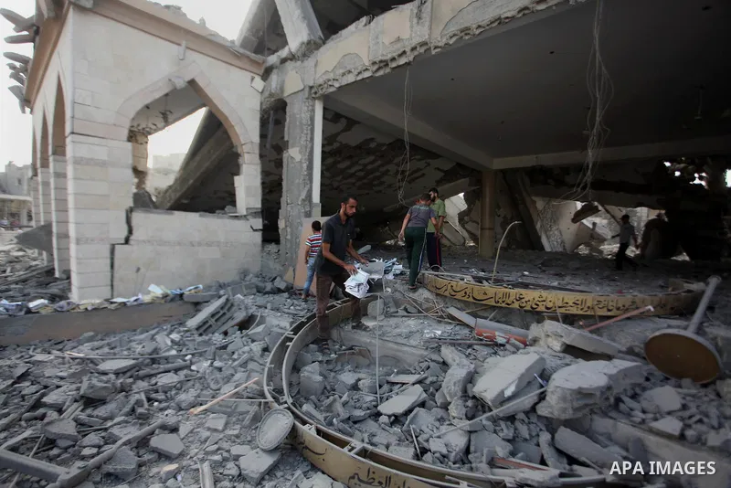 A Palestinian man collects pages of the Koran from the remains of a mosque, which witnesses said was hit by an Israeli air strike, in Beit Hanoun in the northern Gaza Strip August 25, 2014. Israel's Prime Minister Benjam...