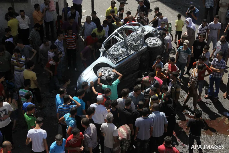 Palestinians surround a wreckage of a car which witnesses said was hit by an Israeli air strike, in Gaza City August 25, 2014. Israeli air strikes killed at least five Palestinians in the Gaza Strip and militants kept up...