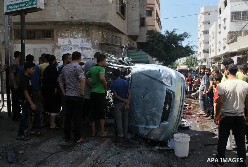 Palestinians surround a wreckage of a car which witnesses said was hit by an Israeli air strike, in Gaza City August 25, 2014. Israeli air strikes killed at least five Palestinians in the Gaza Strip and militants kept up...