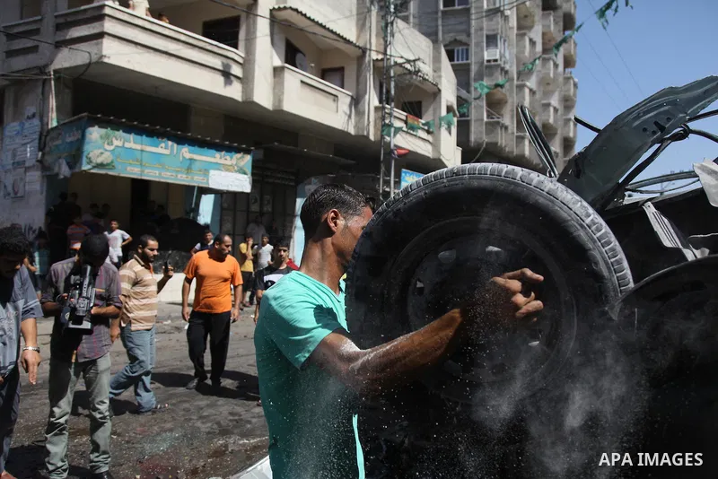A Palestinian cleans a street with a hose after what witnesses said was an Israeli air strike on a car, in Gaza City August 25, 2014. Israeli air strikes killed at least five Palestinians in the Gaza Strip and militants...