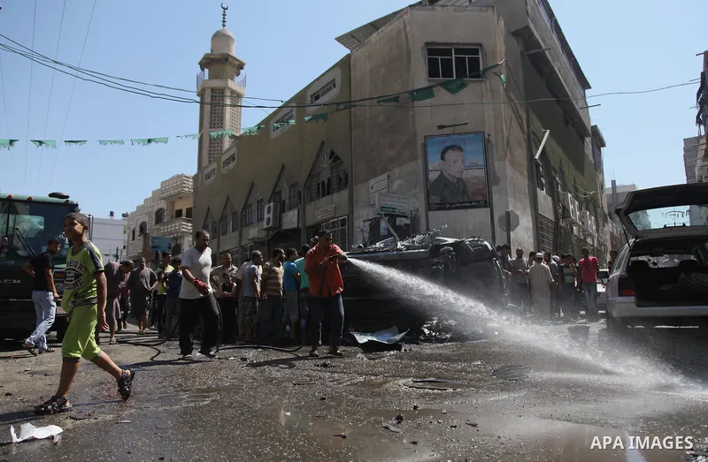 A Palestinian cleans a street with a hose after what witnesses said was an Israeli air strike on a car, in Gaza City August 25, 2014. Israeli air strikes killed at least five Palestinians in the Gaza Strip and militants...