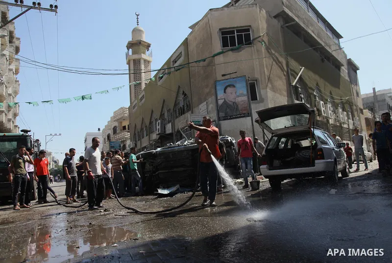 A Palestinian cleans a street with a hose after what witnesses said was an Israeli air strike on a car, in Gaza City August 25, 2014. Israeli air strikes killed at least five Palestinians in the Gaza Strip and militants...