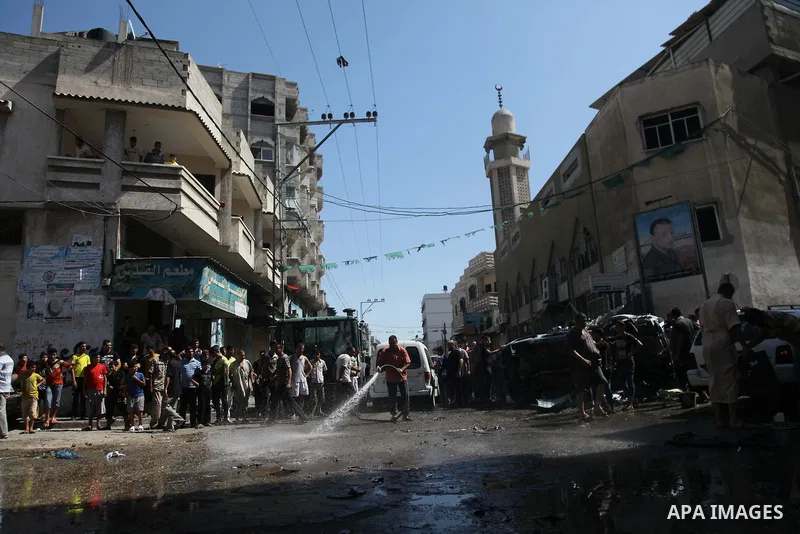 A Palestinian cleans a street with a hose after what witnesses said was an Israeli air strike on a car, in Gaza City August 25, 2014. Israeli air strikes killed at least five Palestinians in the Gaza Strip and militants...