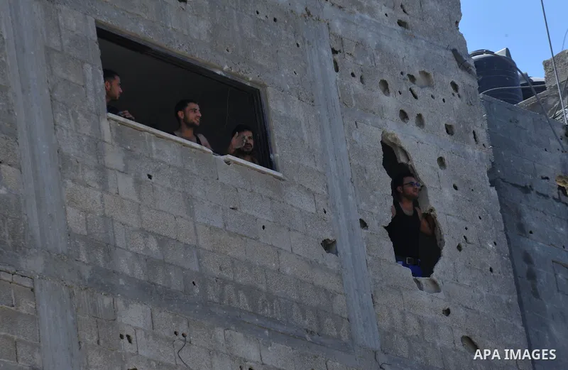 Palestinians look out their house on the rubble of a house targeted in an Israeli air strike in Gaza city on August 25, 2014. Israel's Prime Minister Benjamin Netanyahu warned Palestinian civilians on Sunday to leave imm...
