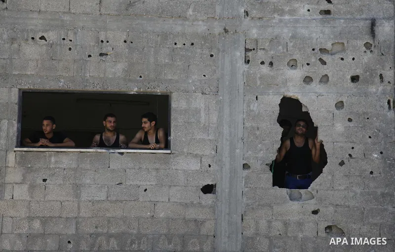Palestinians look out their house on the rubble of a house targeted in an Israeli air strike in Gaza city on August 25, 2014. Israel's Prime Minister Benjamin Netanyahu warned Palestinian civilians on Sunday to leave imm...