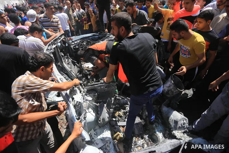 Palestinians gather around the remains of a car, which witnesses said was hit by an Israeli air strike, in Gaza City August 25, 2014. Palestinian and world leaders continue to push for a halt to seven weeks of bloodshed...