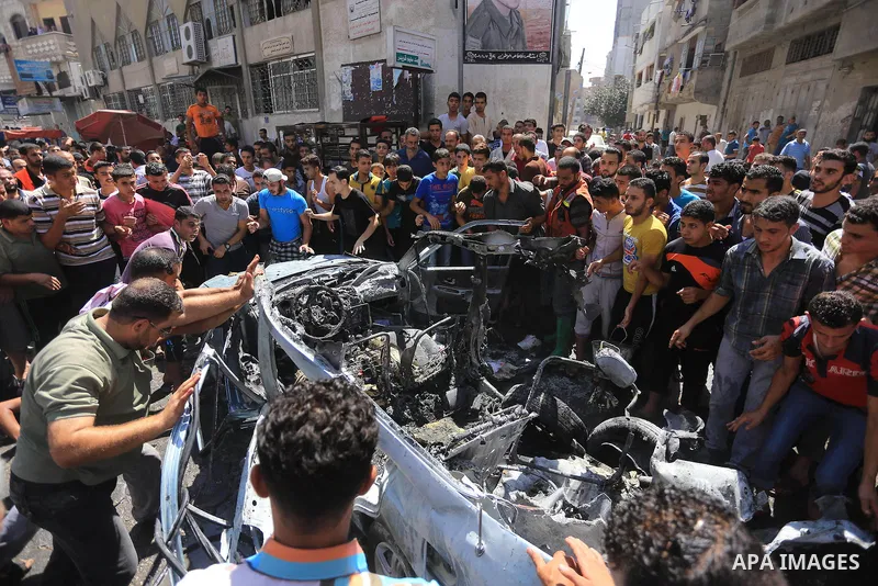 Palestinians gather around the remains of a car, which witnesses said was hit by an Israeli air strike, in Gaza City August 25, 2014. Palestinian and world leaders continue to push for a halt to seven weeks of bloodshed...
