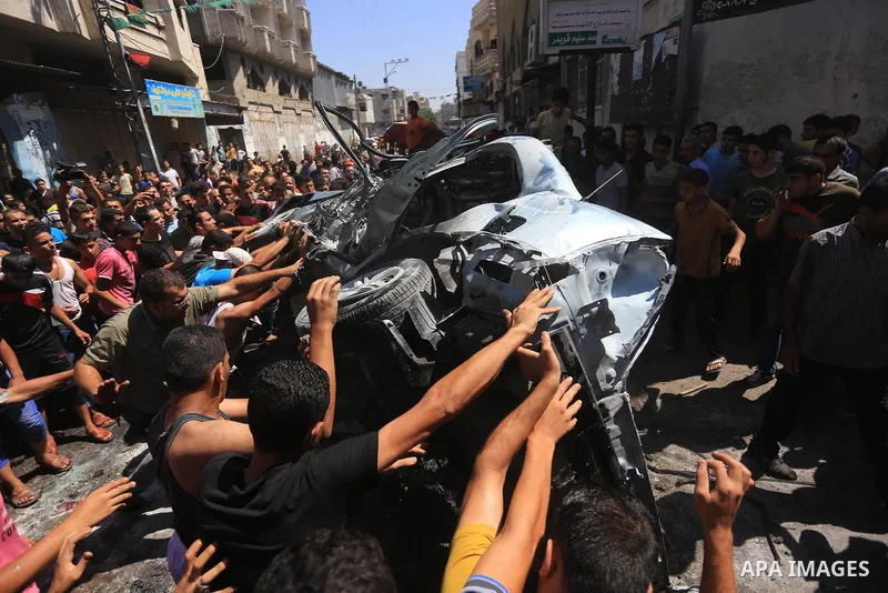 Palestinians gather around the remains of a car, which witnesses said was hit by an Israeli air strike, in Gaza City August 25, 2014. Palestinian and world leaders continue to push for a halt to seven weeks of bloodshed...