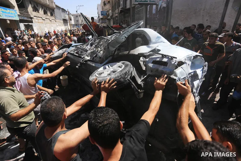 Palestinians gather around the remains of a car, which witnesses said was hit by an Israeli air strike, in Gaza City August 25, 2014. Palestinian and world leaders continue to push for a halt to seven weeks of bloodshed...