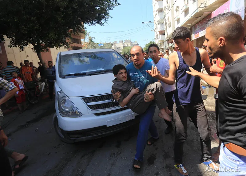 Palestinians gather around the remains of a car, which witnesses said was hit by an Israeli air strike, in Gaza City August 25, 2014. Palestinian and world leaders continue to push for a halt to seven weeks of bloodshed...