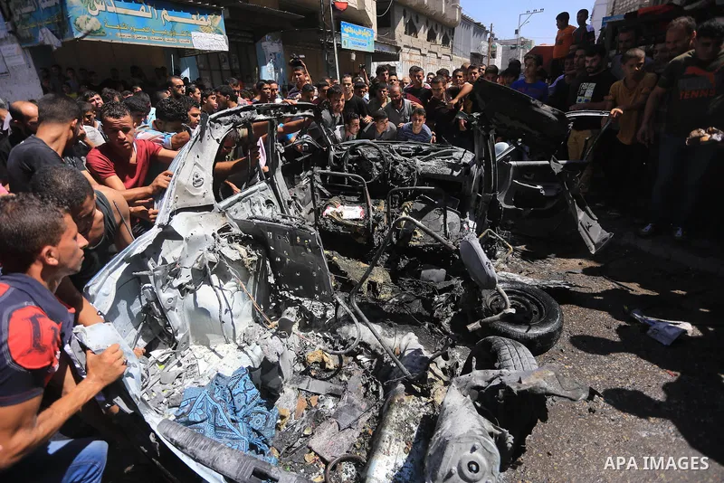 Palestinians gather around the remains of a car, which witnesses said was hit by an Israeli air strike, in Gaza City August 25, 2014. Palestinian and world leaders continue to push for a halt to seven weeks of bloodshed...