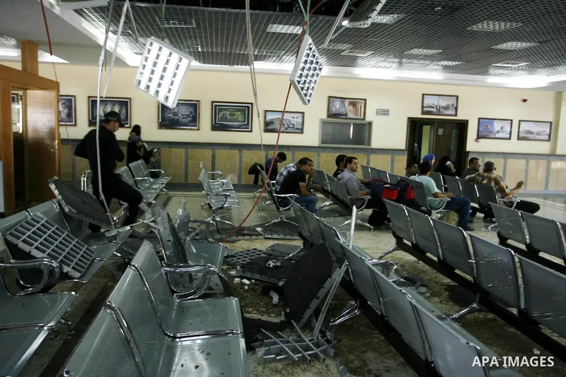 Palestinian travellers wait before crossing into Egypt near damage, from an Israeli air strike, in the departure lounge of the Rafah border crossing with Egypt in the southern Gaza Strip on August 25, 2014. Violence reve...