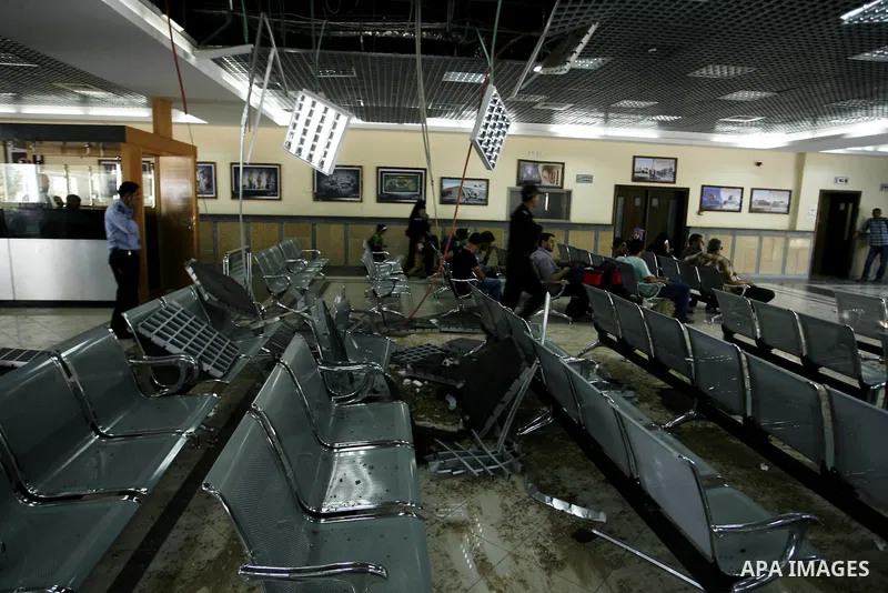 Palestinian travellers wait before crossing into Egypt near damage, from an Israeli air strike, in the departure lounge of the Rafah border crossing with Egypt in the southern Gaza Strip on August 25, 2014. Violence reve...