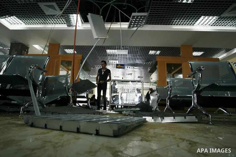 Palestinian travellers wait before crossing into Egypt near damage, from an Israeli air strike, in the departure lounge of the Rafah border crossing with Egypt in the southern Gaza Strip on August 25, 2014. Violence reve...