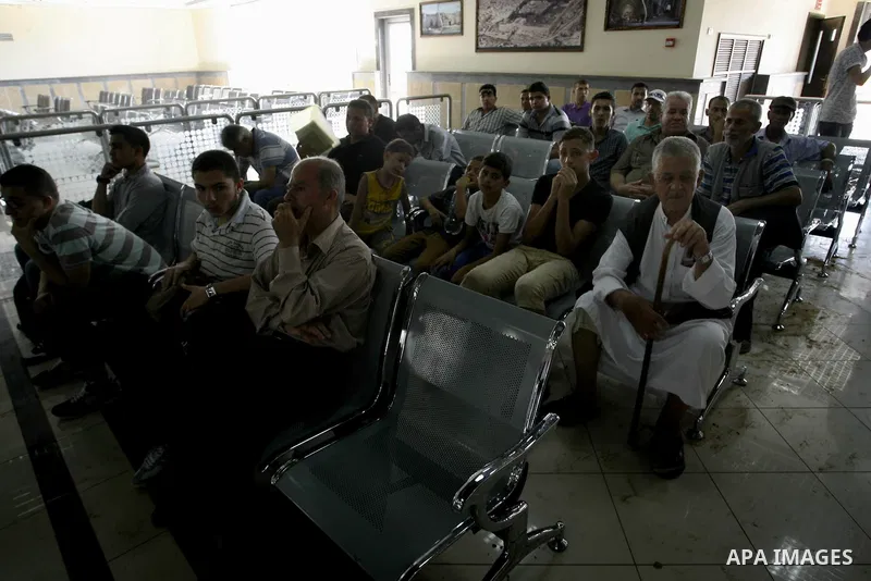 Palestinian travellers wait before crossing into Egypt near damage, from an Israeli air strike, in the departure lounge of the Rafah border crossing with Egypt in the southern Gaza Strip on August 25, 2014. Violence reve...