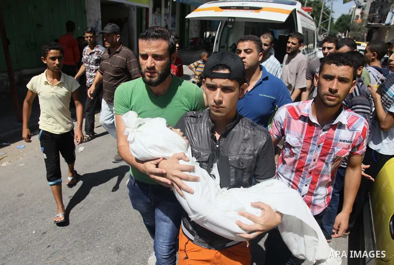 Palestinian mourners carry the body of boy,during his funeral in Gaza City, whom medics said was killed in an Israeli air strike on August 25, 2014. Photo by Ezz al-Zanoun
