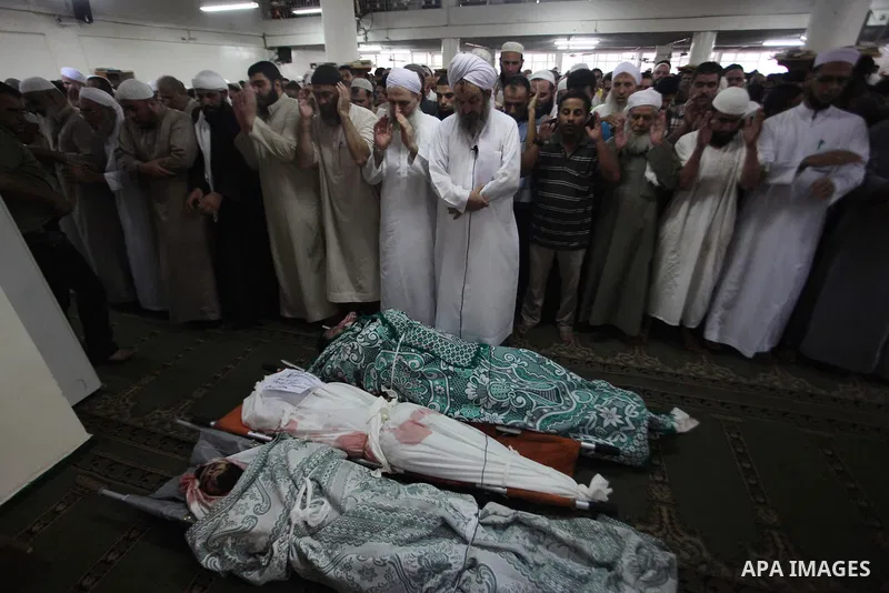 Palestinians mourn over the bodies of Basim Hijazi 36, his brother Ahmed, 26, and a friend Mohamad al-Dali who were killed when their car was hit by an Israeli air strike during their funeral in Gaza City on August 25, 2...