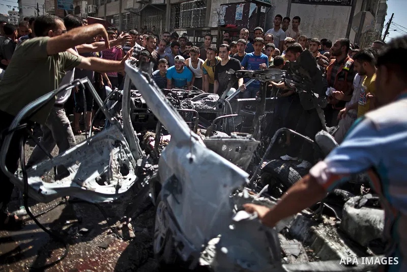 Palestinians gather around the remains of a car, which witnesses said was hit by an Israeli air strike, in Gaza City August 25, 2014. Palestinian and world leaders continue to push for a halt to seven weeks of bloodshed...