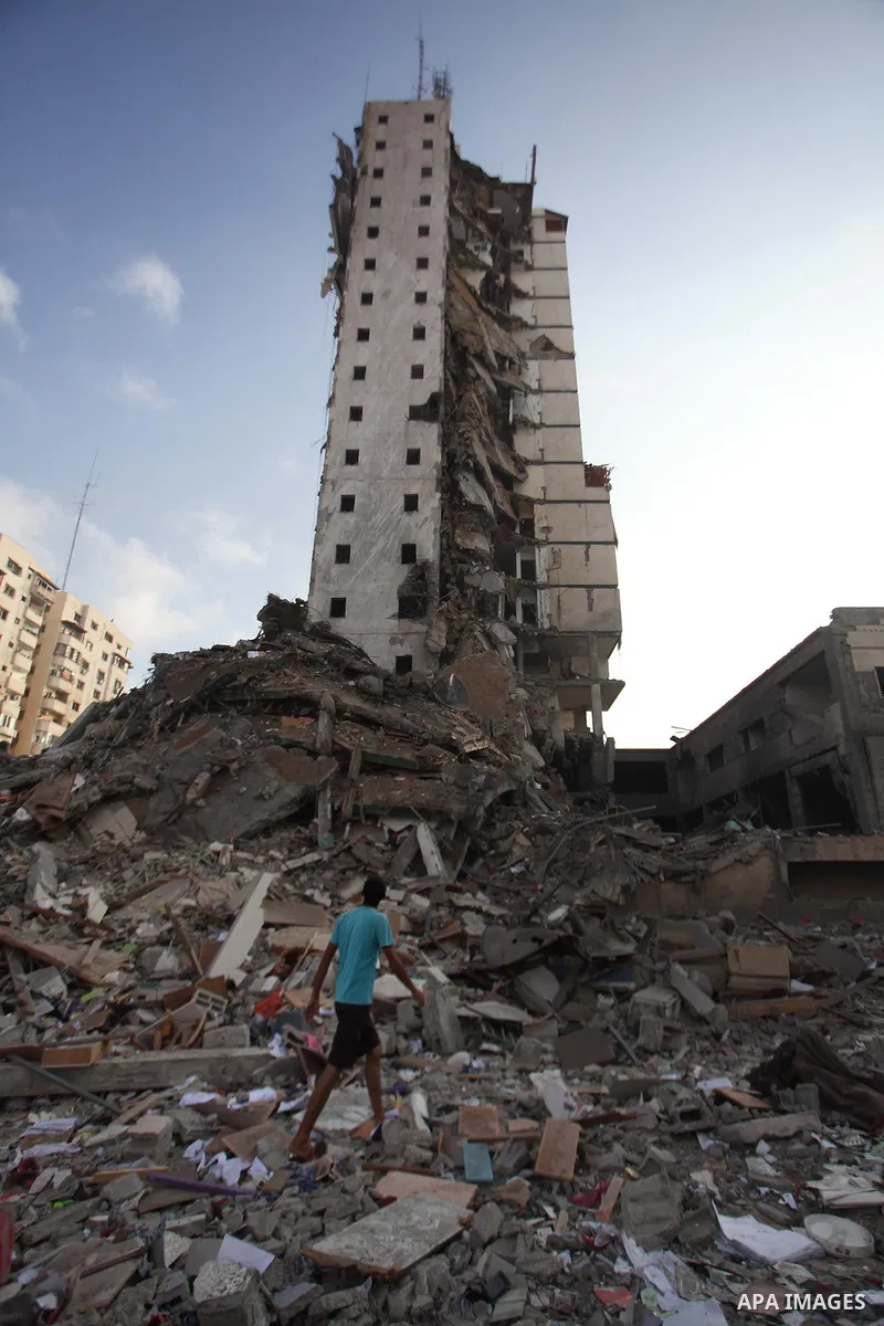 A Palestinian boy stands next to the remains of one of Gaza's tallest apartment towers, which witnesses said was hit by an Israeli air strike that destroyed much of it, in Gaza City August 26, 2014. Israeli air strikes l...