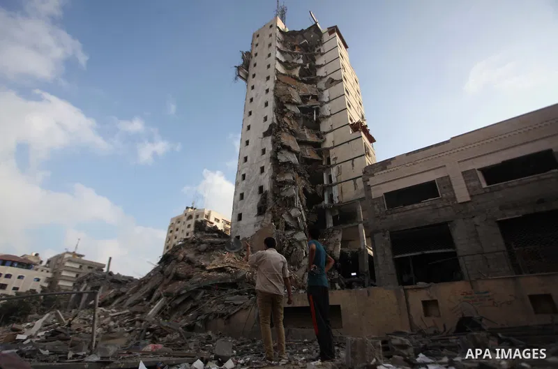 Palestinians stand next to the remains of one of Gaza's tallest apartment towers, which witnesses said was hit by an Israeli air strike that destroyed much of it, in Gaza City August 26, 2014. Israeli air strikes launche...