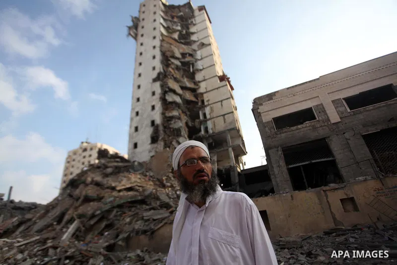 A Palestinian man stands next to the remains of one of Gaza's tallest apartment towers, which witnesses said was hit by an Israeli air strike that destroyed much of it, in Gaza City August 26, 2014. Israeli air strikes l...