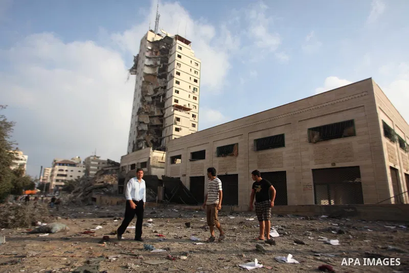 Palestinians stand next to the remains of one of Gaza's tallest apartment towers, which witnesses said was hit by an Israeli air strike that destroyed much of it, in Gaza City August 26, 2014. Israeli air strikes launche...