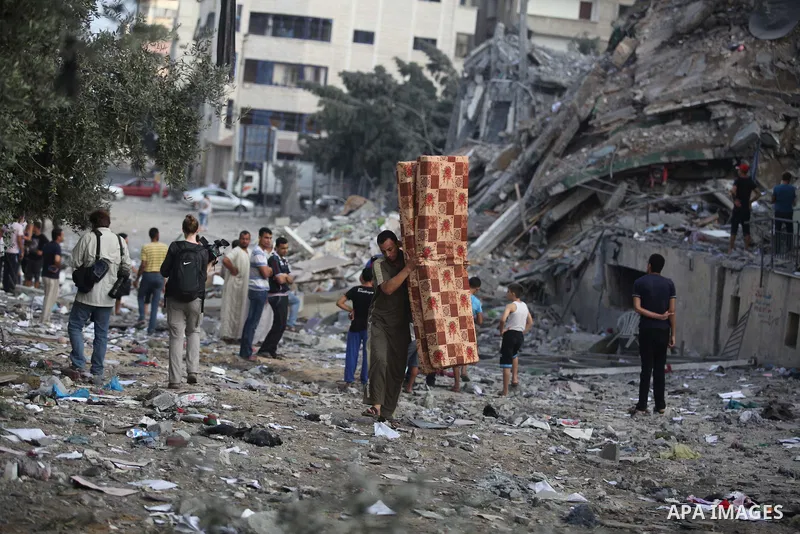 Palestinians collect their belongings from under the rubble of one of Gaza's tallest apartment towers, which witnesses said was hit by an Israeli air strike that destroyed much of it, in Gaza City August 26, 2014. Israel...