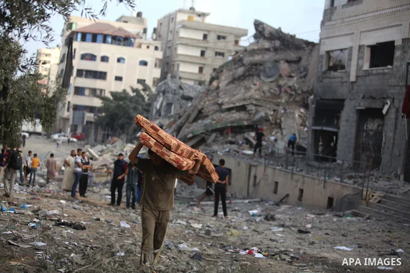 Palestinians collect their belongings from under the rubble of one of Gaza's tallest apartment towers, which witnesses said was hit by an Israeli air strike that destroyed much of it, in Gaza City August 26, 2014. Israel...
