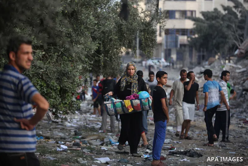 Palestinians collect their belongings from under the rubble of one of Gaza's tallest apartment towers, which witnesses said was hit by an Israeli air strike that destroyed much of it, in Gaza City August 26, 2014. Israel...