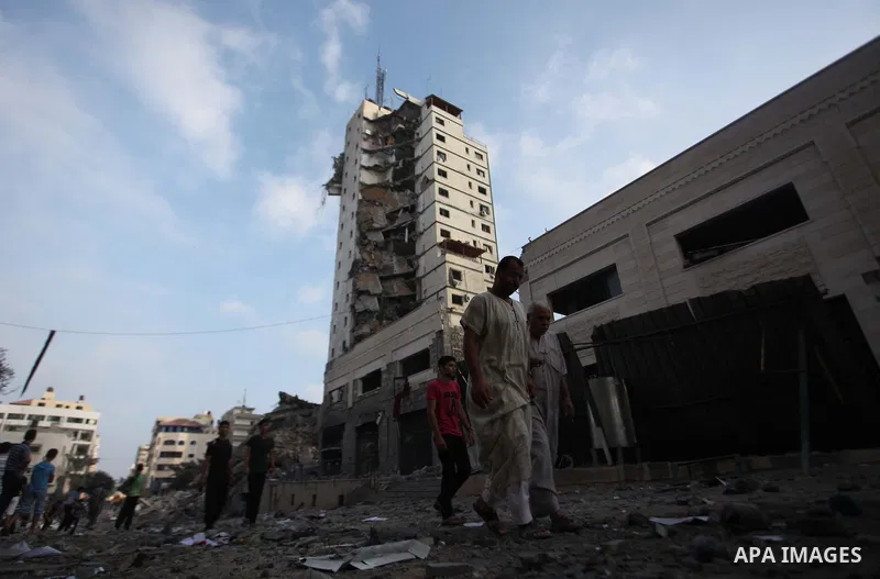 Palestinians stand next to the remains of one of Gaza's tallest apartment towers, which witnesses said was hit by an Israeli air strike that destroyed much of it, in Gaza City August 26, 2014. Israeli air strikes launche...