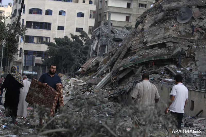 Palestinians collect their belongings from under the rubble of one of Gaza's tallest apartment towers, which witnesses said was hit by an Israeli air strike that destroyed much of it, in Gaza City August 26, 2014. Israel...