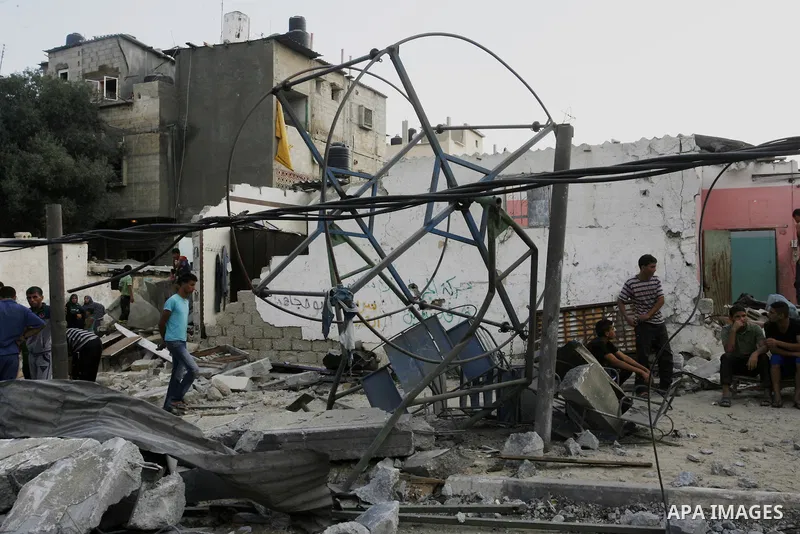 Palestinian children play around a destroyed mini ferris wheel near the remains of homes that were destroyed by an Israeli air strike on Rafah town in the southern Gaza Strip on August 26, 2014. Israeli fire killed 10 Pa...