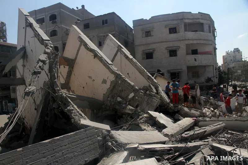 Palestinians gather around the remains of a tower building housing offices which witnesses said was destroyed by an Israeli air strike in Gaza City August 26, 2014. Israeli air strikes launched before dawn on Tuesday kil...