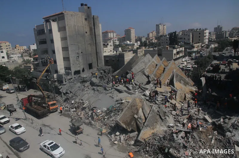 Palestinians gather around the remains of a tower building housing offices which witnesses said was destroyed by an Israeli air strike in Gaza City August 26, 2014. Israeli air strikes launched before dawn on Tuesday kil...