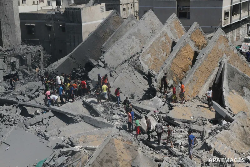 Palestinians gather around the remains of a tower building housing offices which witnesses said was destroyed by an Israeli air strike in Gaza City August 26, 2014. Israeli air strikes launched before dawn on Tuesday kil...