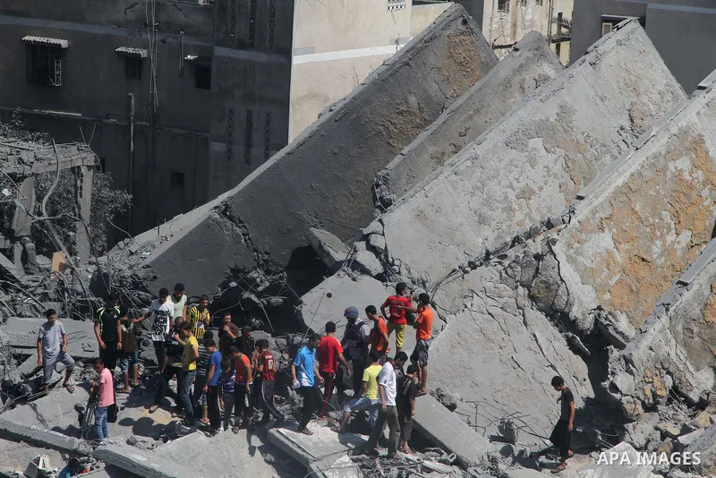 Palestinians gather around the remains of a tower building housing offices which witnesses said was destroyed by an Israeli air strike in Gaza City August 26, 2014. Israeli air strikes launched before dawn on Tuesday kil...