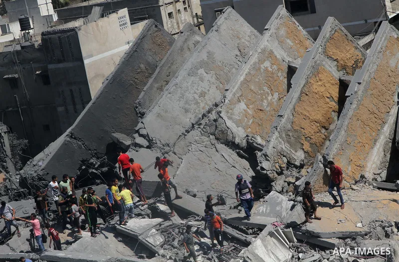 Palestinians gather around the remains of a tower building housing offices which witnesses said was destroyed by an Israeli air strike in Gaza City August 26, 2014. Israeli air strikes launched before dawn on Tuesday kil...