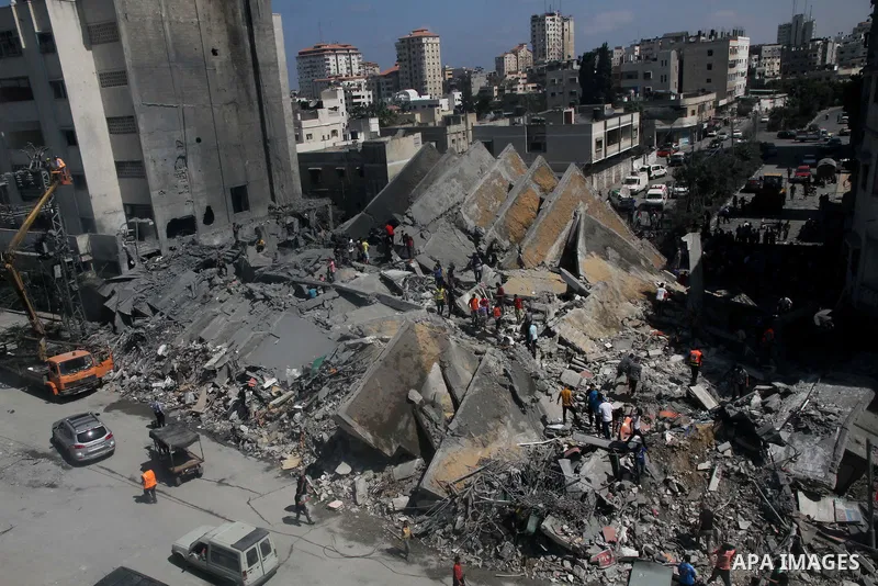 Palestinians gather around the remains of a tower building housing offices which witnesses said was destroyed by an Israeli air strike in Gaza City August 26, 2014. Israeli air strikes launched before dawn on Tuesday kil...