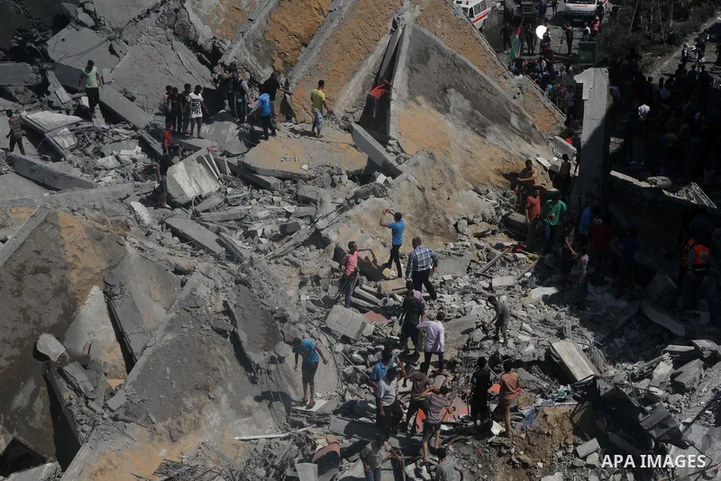Palestinians gather around the remains of a tower building housing offices which witnesses said was destroyed by an Israeli air strike in Gaza City August 26, 2014. Israeli air strikes launched before dawn on Tuesday kil...