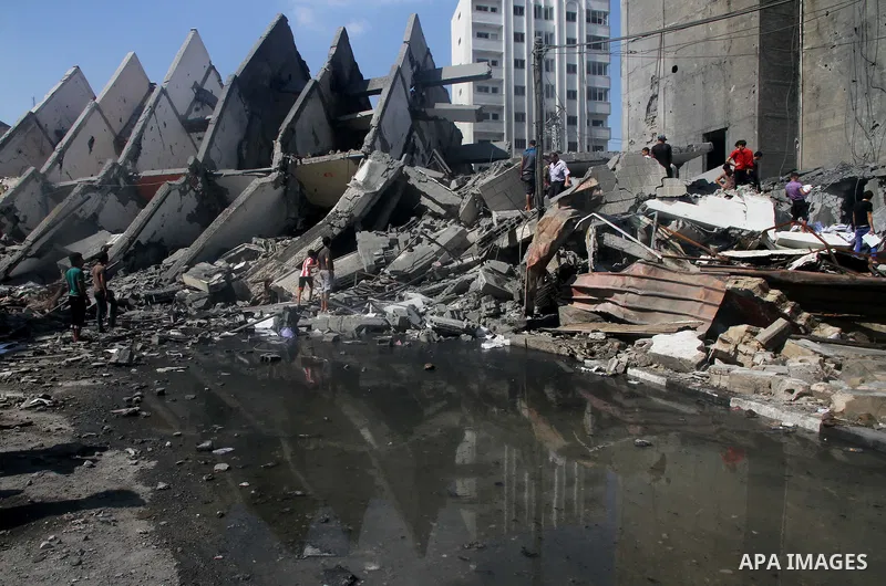 Palestinians gather around the remains of a tower building housing offices which witnesses said was destroyed by an Israeli air strike in Gaza City August 26, 2014. Israeli air strikes launched before dawn on Tuesday kil...